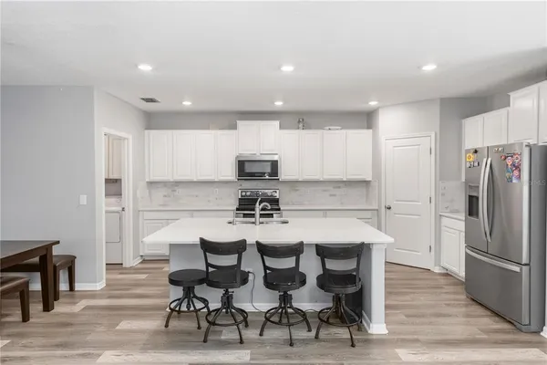 a kitchen with kitchen island white cabinets and stainless steel appliances