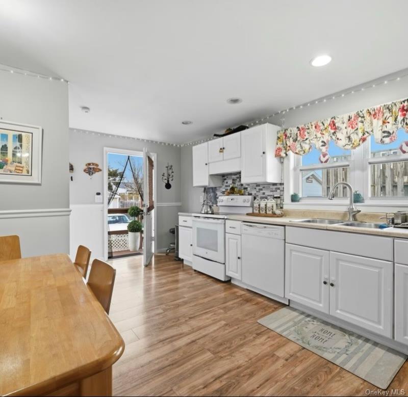 21 Locust Riverhead, NY 11901 - Photo 7 of 14 a kitchen with stainless steel appliances granite countertop a stove a sink dishwasher and a refrigerator with wooden floor