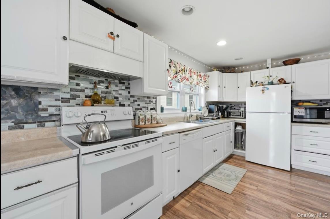 21 Locust Riverhead, NY 11901 - Photo 8 of 14 a kitchen with white cabinets and white appliances