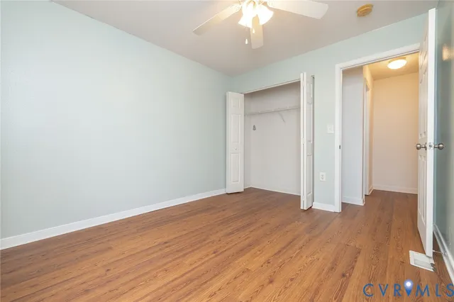 an empty room with wooden floor and a ceiling fan