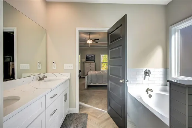 a en suite bathroom with a double vanity sink a mirror and a bathtub
