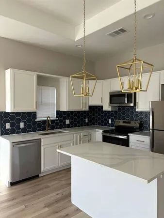 a kitchen with stainless steel appliances granite countertop a sink a stove and a wooden floors
