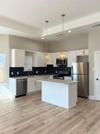 a kitchen with stainless steel appliances a refrigerator sink and white cabinets