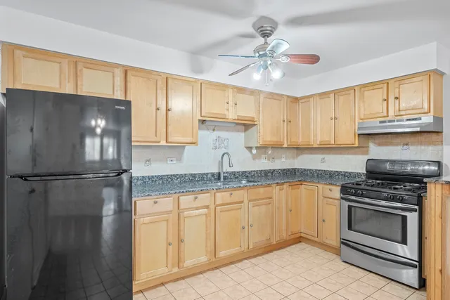a kitchen with granite countertop a refrigerator sink and cabinets