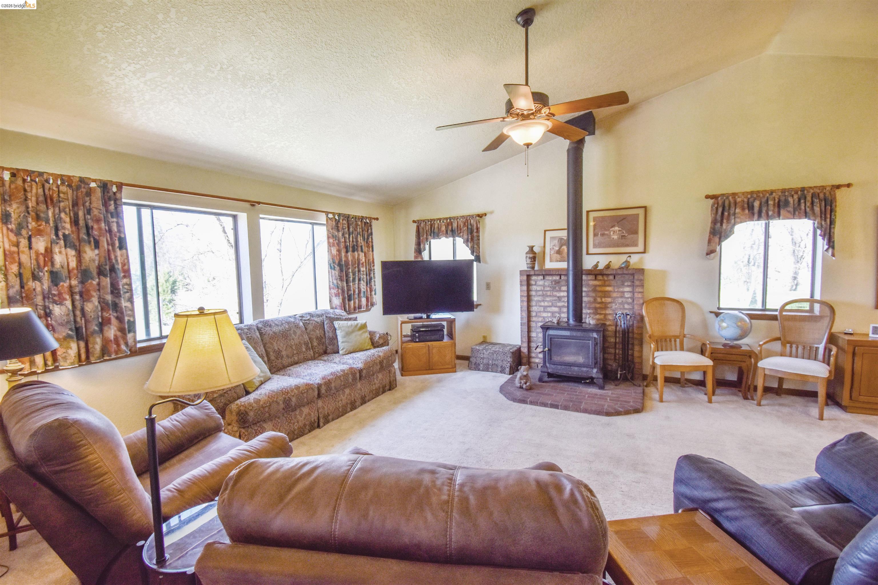 15170 Potato Ranch Road Sonora, CA 95370 - Photo 7 of 49 Carpeted living room featuring a wood stove and ceiling fan