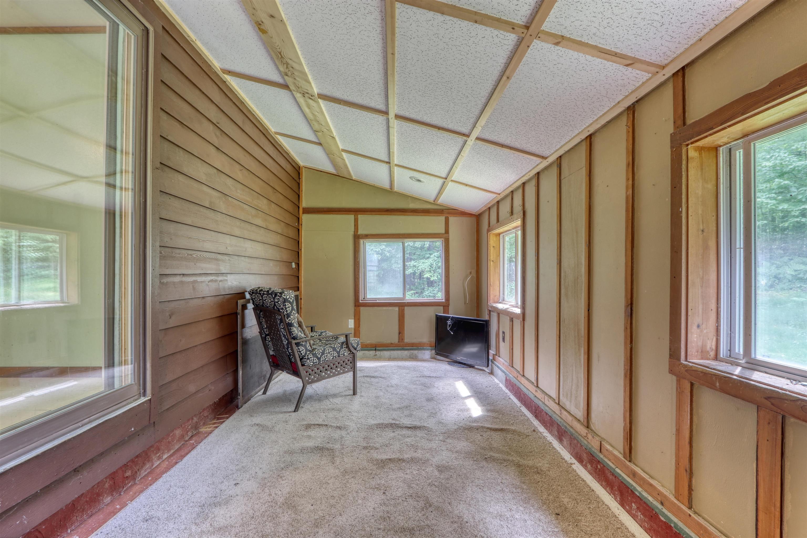 22655 Sunset Acres Lane Grand View, WI 54839 - Photo 23 of 47 Unfurnished room featuring vaulted ceiling, plenty of natural light, wood walls, and carpet