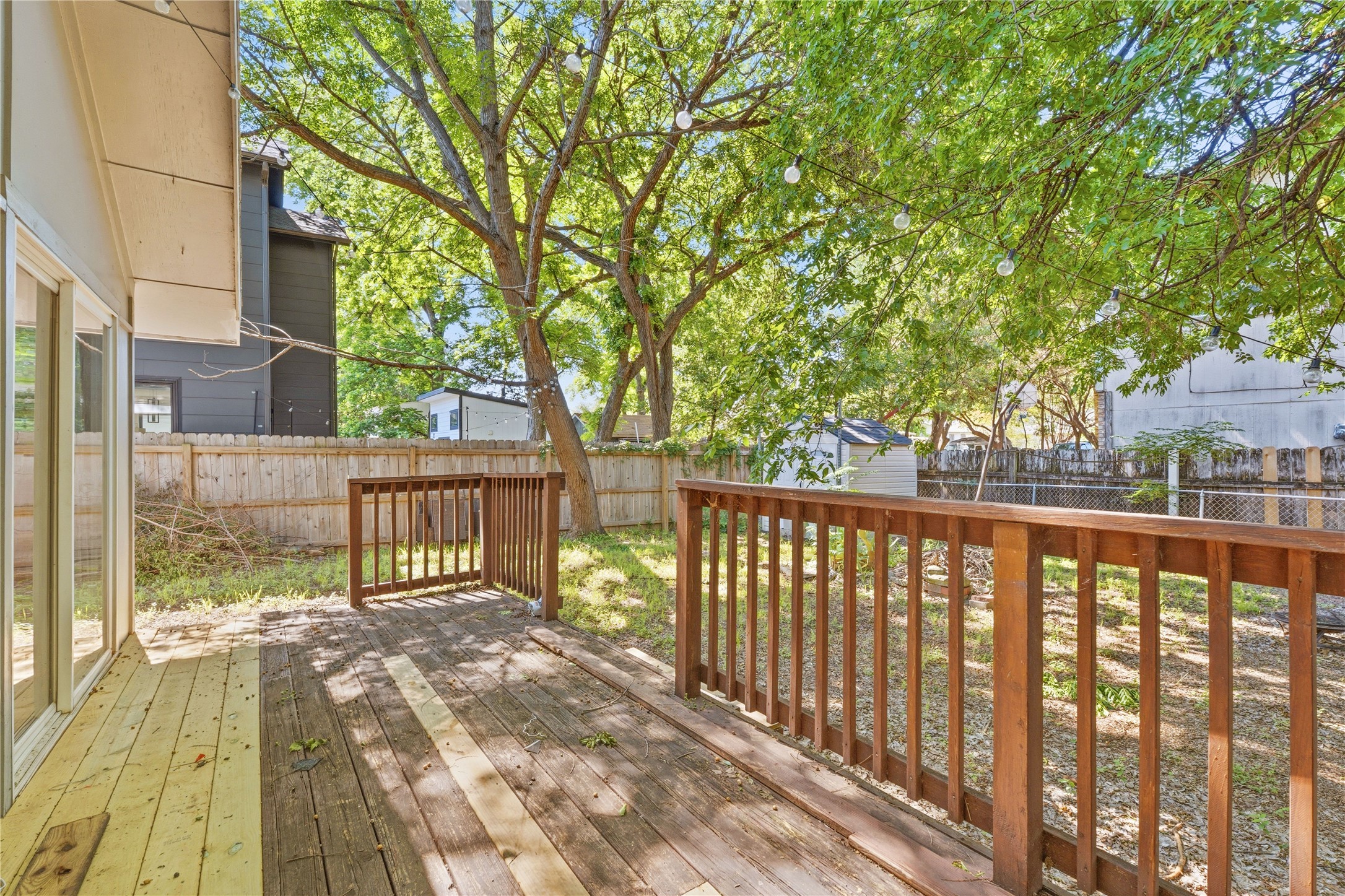 2207 Santa Rita Street Austin, TX 78702 - Photo 12 of 15 Spacious backyard featuring a wood deck with railing, mature trees, a privacy fence, and a storage shed