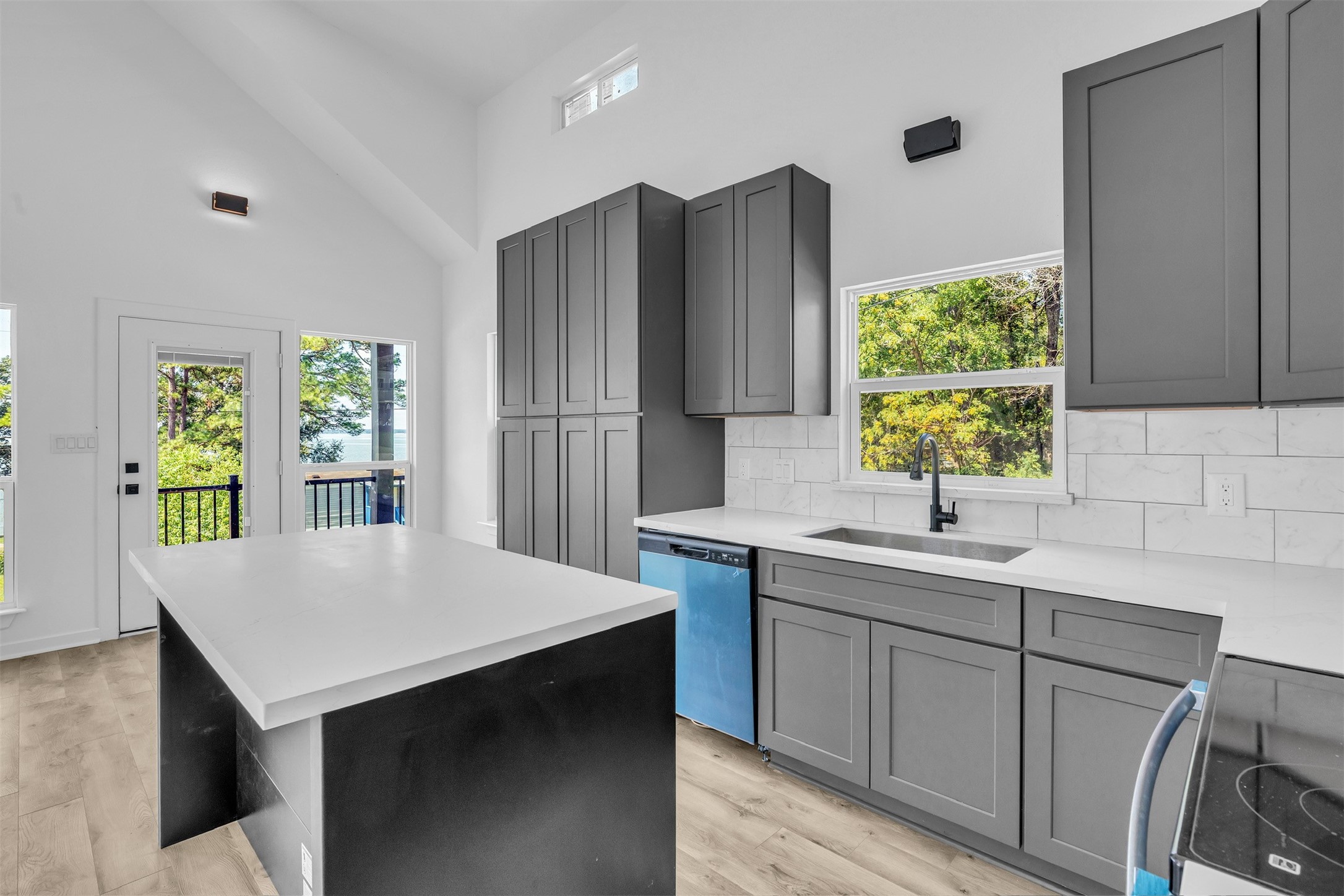 117 Rain Forest Road Onalaska, TX 77360 - Photo 14 of 30 Experience modern elegance in this sleek kitchen with its striking dark cabinetry, expansive countertops, and abundant natural light, all beautifully framed by picturesque views.