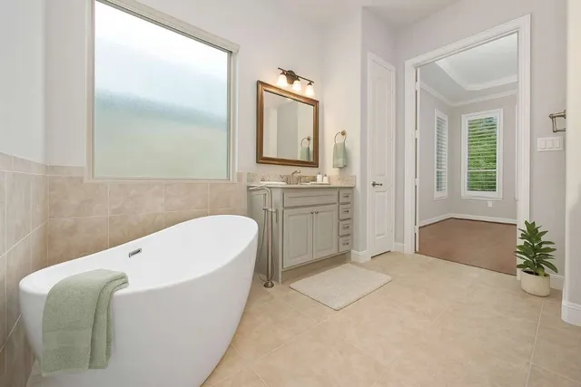 a spacious bathroom with a tub sink and mirror