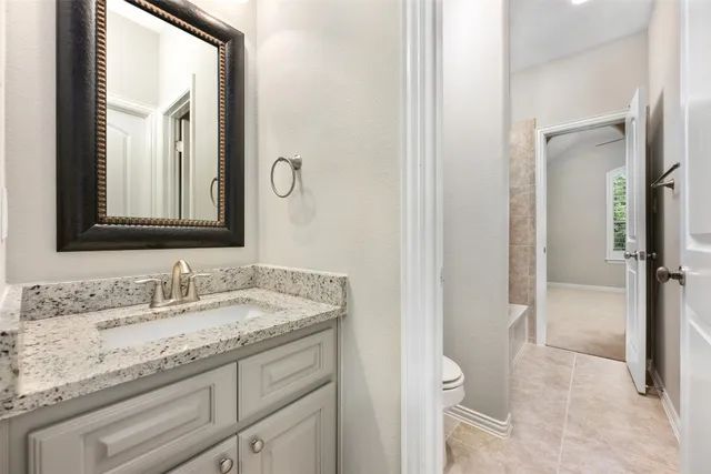 a bathroom with a granite countertop toilet a sink and a mirror