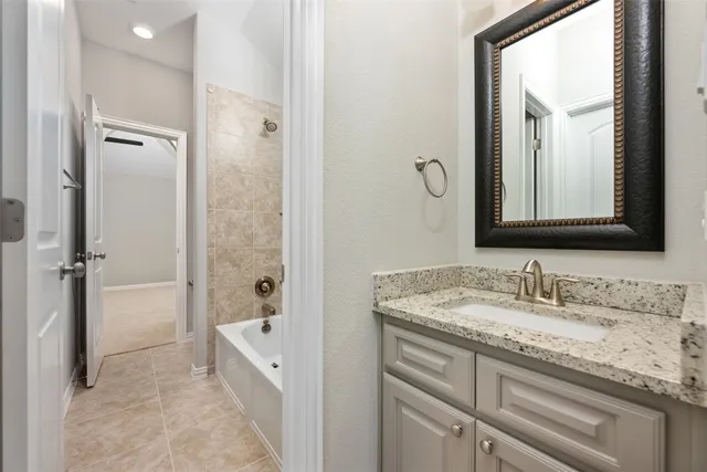 a bathroom with a granite countertop sink mirror and a bathtub