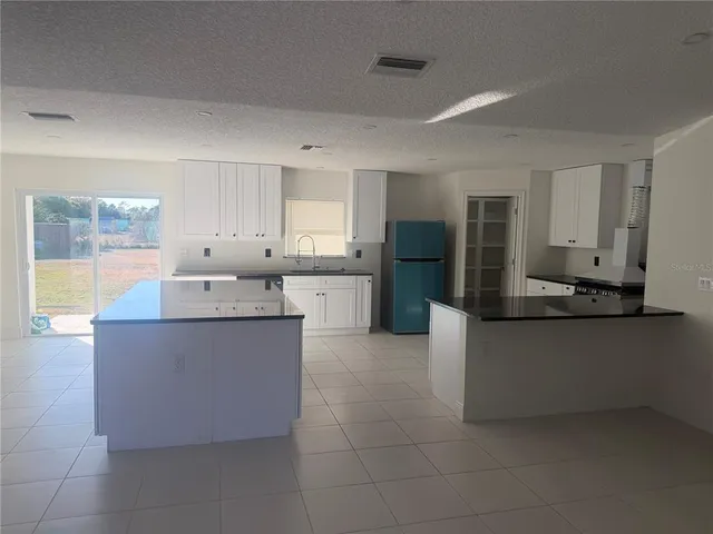 a kitchen with stainless steel appliances granite countertop a refrigerator a sink and white cabinets