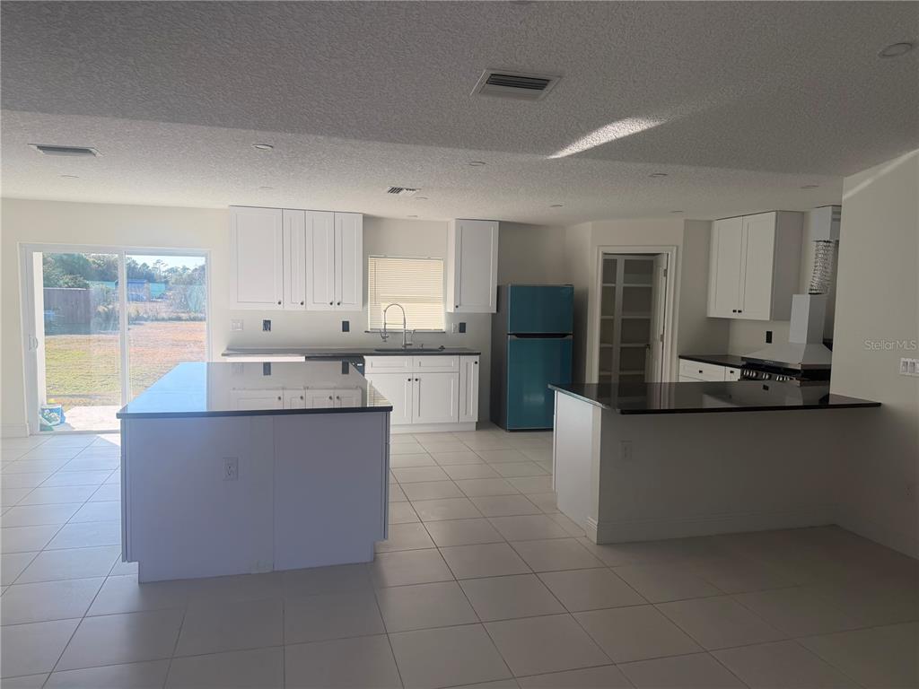3444 Packard Avenue St. Cloud, FL 34772 - Photo 12 of 28 a kitchen with stainless steel appliances granite countertop a sink and a refrigerator