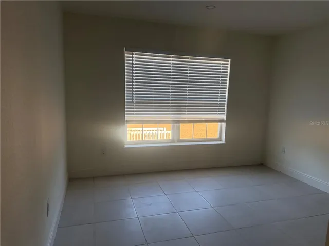 a view of an empty room with closet and a window