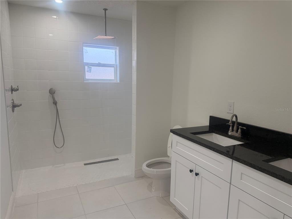 3444 Packard Avenue St. Cloud, FL 34772 - Photo 25 of 28 a bathroom with a granite countertop sink a toilet and a shower