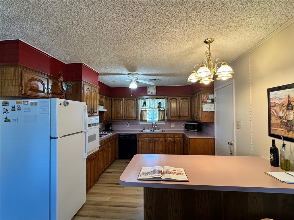 915 Maple Shade Road Alma, AR 72921 - Photo 14 of 18 Kitchen with white appliances, light countertops, a peninsula, wood finish cabinetry, and a textured ceiling