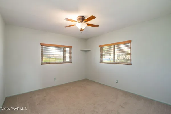 an empty room with windows and ceiling fan