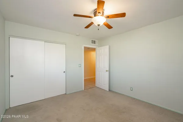 an empty room with closet and a chandelier fan