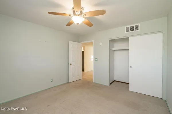 an empty room with closet and a chandelier fan