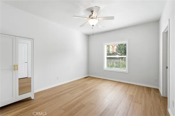 an empty room with wooden floor and fan