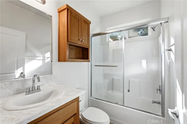 an empty room with wooden floor chandelier fan and windows