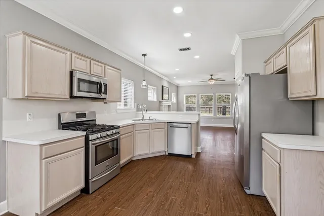 a kitchen with stainless steel appliances granite countertop a stove top oven a sink dishwasher and a refrigerator with wooden floor