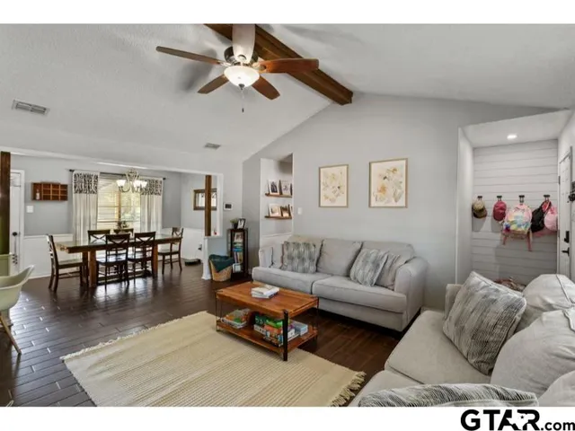 a living room with furniture and a dining table with wooden floor