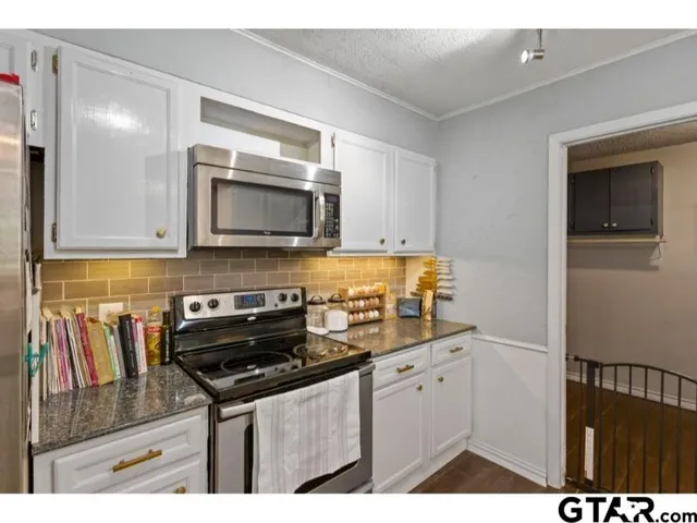 a kitchen with granite countertop a stove and a microwave