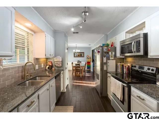 a kitchen with stainless steel appliances granite countertop a sink stove and refrigerator