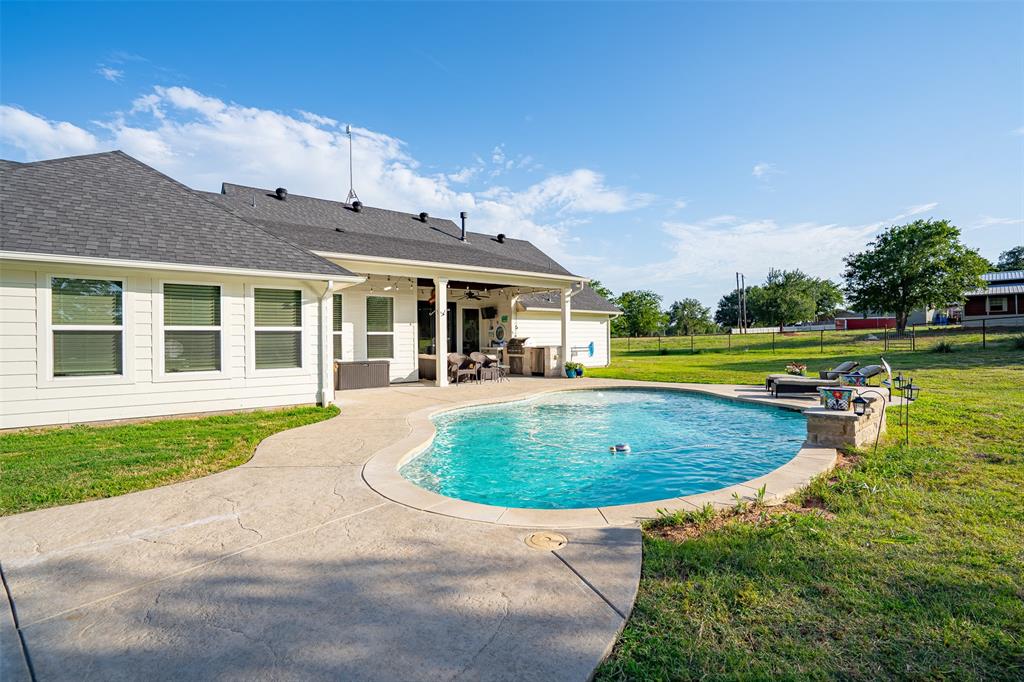 1920 Meander Road Granbury, TX 76049 - Photo 27 of 40 Rear exterior featuring a freeform swimming pool, stamped concrete pool deck, covered patio, and white siding