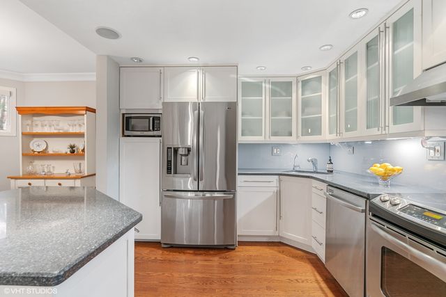 a kitchen with stainless steel appliances granite countertop a refrigerator a stove and a sink with wooden floor