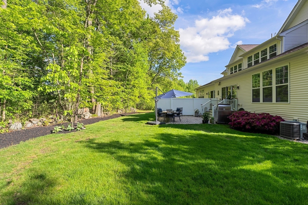 2 Hummingbird Way, Unit 1 Methuen, MA 01844 - Photo 36 of 42 a backyard of a house with plants and large trees