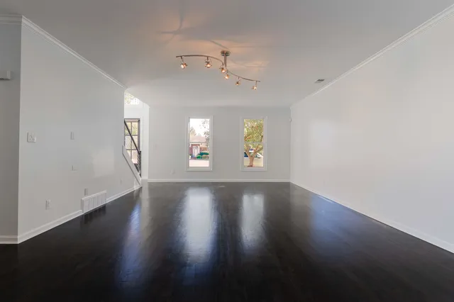 an empty room with wooden floor and windows