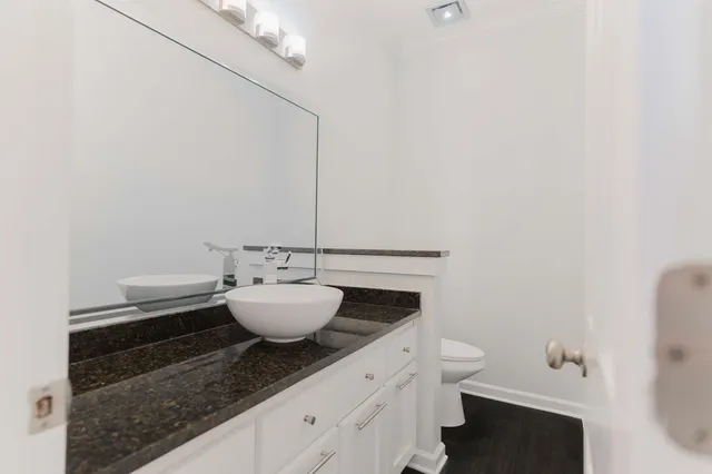 a bathroom with a granite countertop toilet and a sink