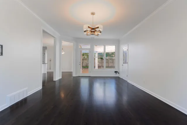 an empty room with wooden floor chandelier fan and windows