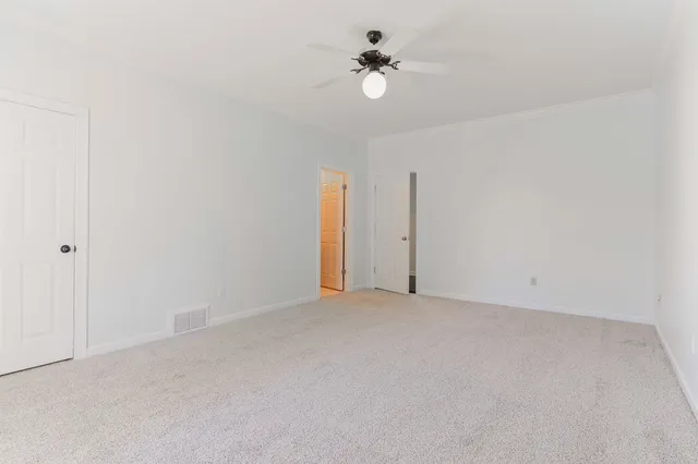 a view of an empty room with a chandelier fan