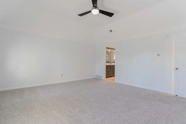 an empty room with a ceiling fan and carpet
