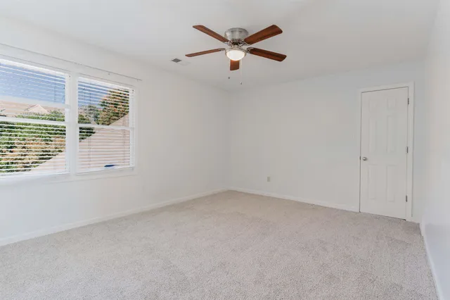 an empty room with a window and a ceiling fan