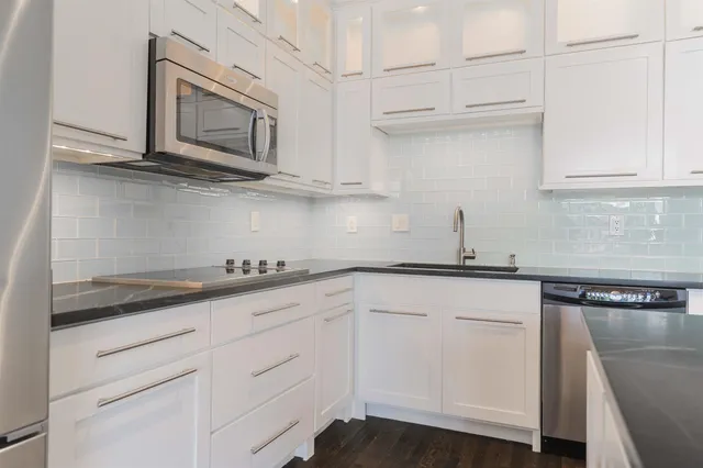 a kitchen with stainless steel appliances granite countertop white cabinets sink and dishwasher