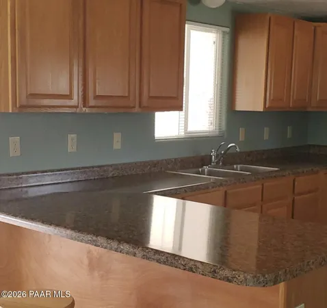 a kitchen with granite countertop white cabinets sink and window