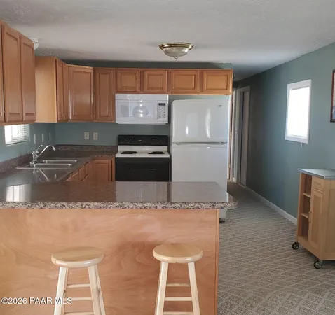 a kitchen with granite countertop a sink a stove and refrigerator