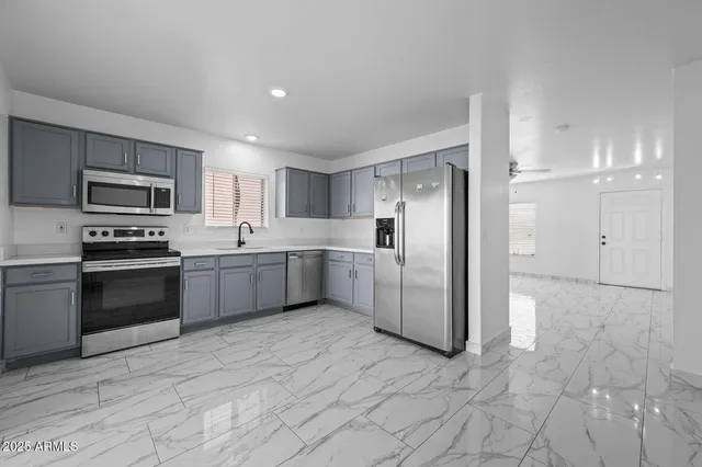 a kitchen with stainless steel appliances a refrigerator a sink a stove top oven and cabinets
