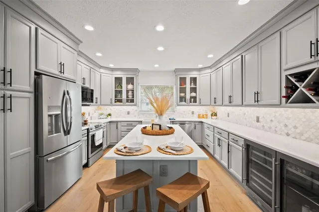 a kitchen with stainless steel appliances granite countertop a refrigerator a sink dishwasher and white cabinets with wooden floor