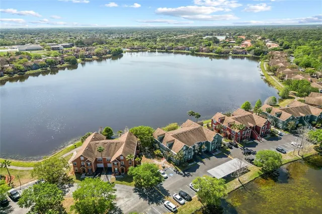 an aerial view of a house with lake view and a floor to ceiling window next to a yard