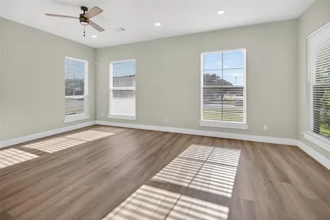 an empty room with wooden floor cabinet and windows