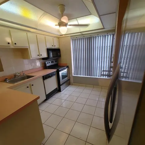 a kitchen with stainless steel appliances a sink a stove top oven a chimney and cabinets