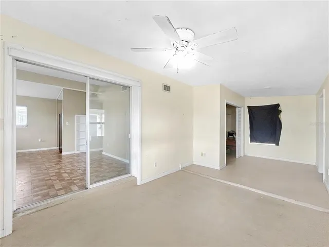 a view of a livingroom with a chandelier fan and windows