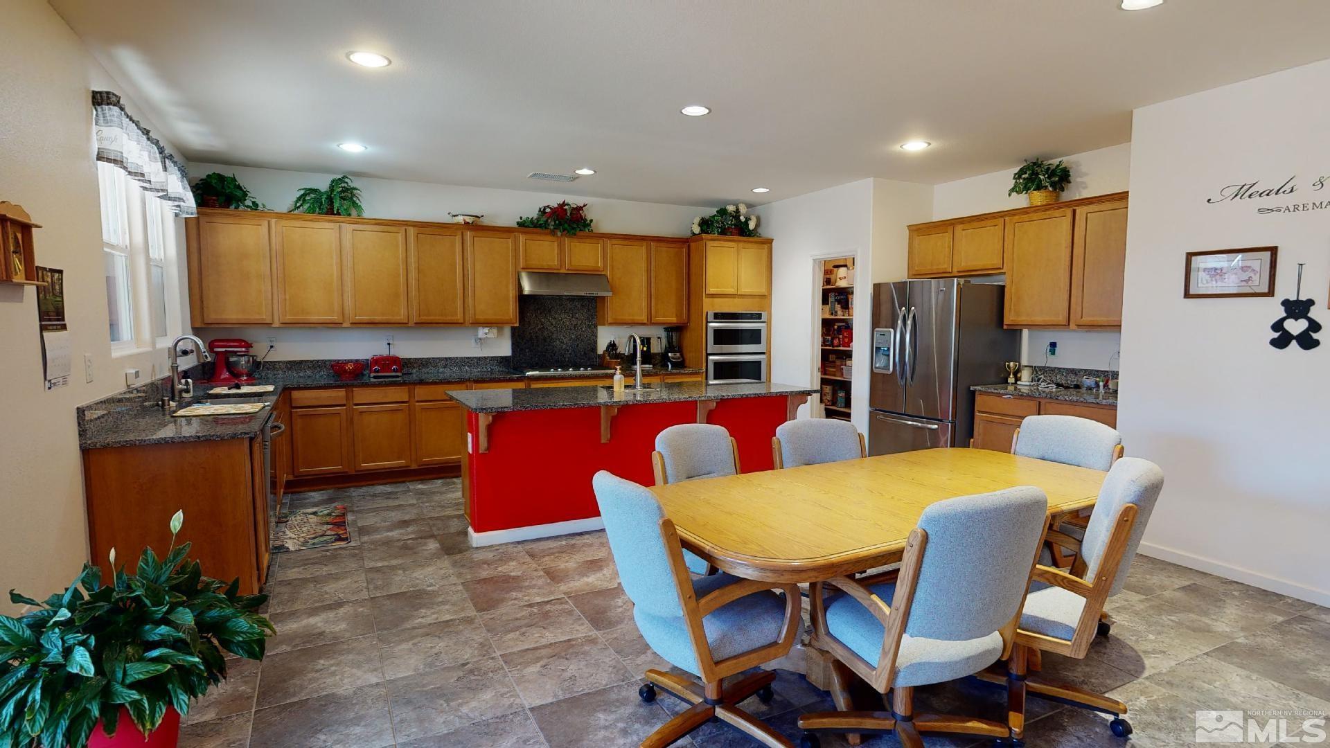 9810 Kerrydale Court Reno, NV 89521 - Photo 5 of 40 a kitchen with stainless steel appliances kitchen island granite countertop a refrigerator a stove a sink dishwasher with a dining table and chairs