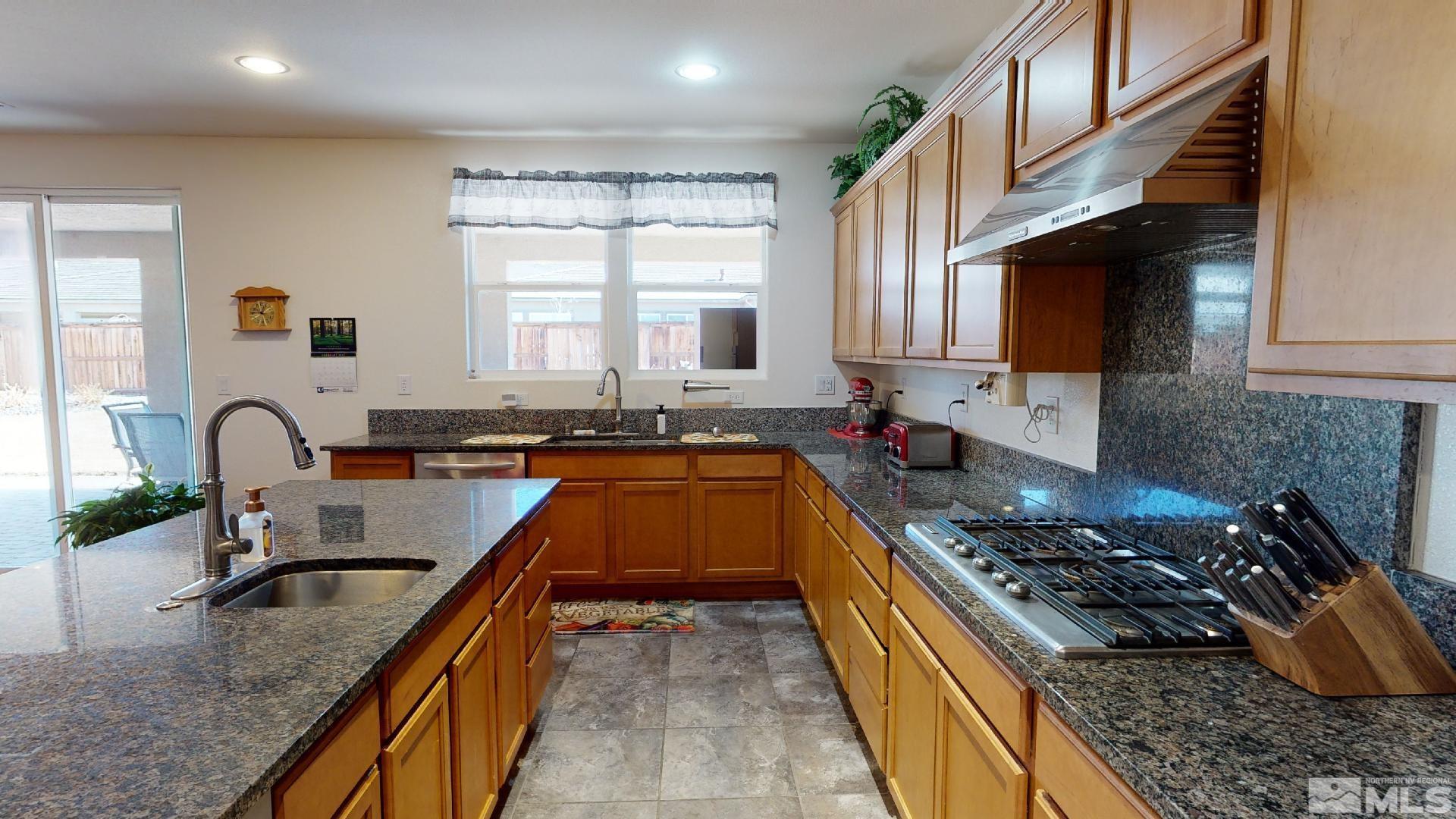 9810 Kerrydale Court Reno, NV 89521 - Photo 8 of 40 a kitchen with kitchen island granite countertop a sink a counter top space and cabinets