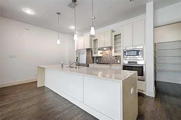 a large kitchen with kitchen island a stove a sink a center island and wooden floor